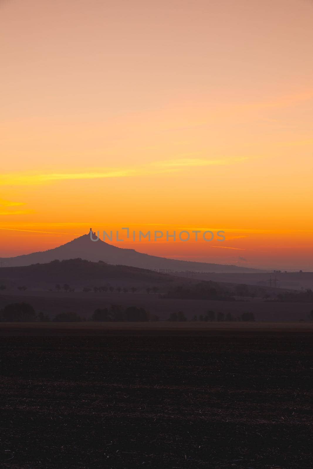 The silhouette of Hazmburk Castle at sunrise.Central Bohemian Uplands,Czech Republic. At the top of the mountain there is the ruin of a mediaeval castle, of which two towers and some wall fragments are still standing.