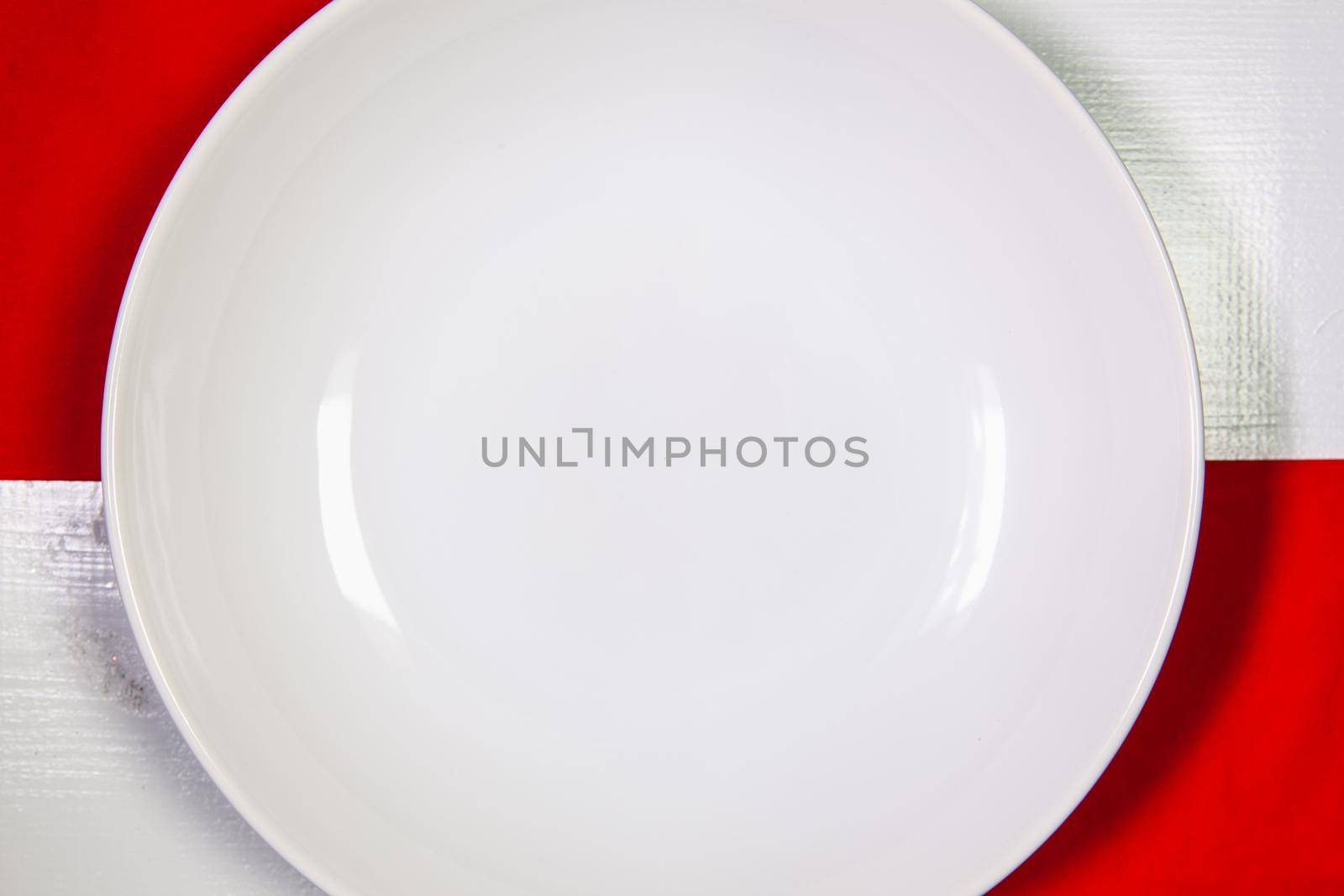 White plate and red Christmas decoration on the table. by CaptureLight