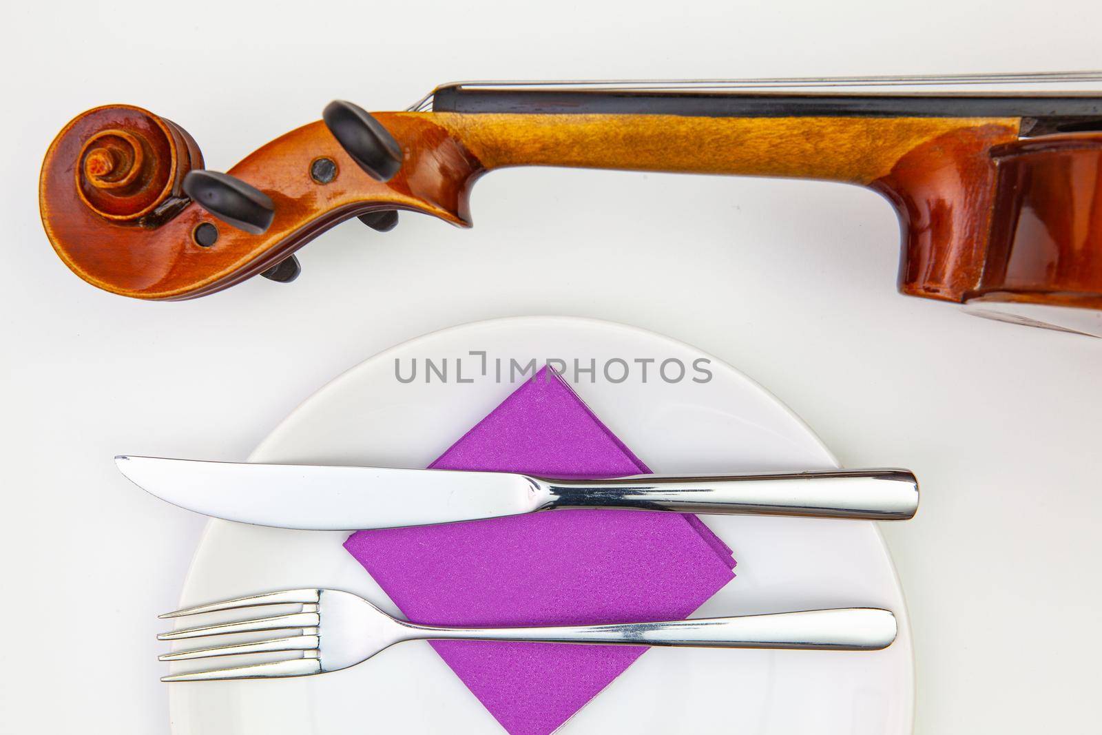 Symphony of taste. White plate and old violin on the white  wooden table.Top view. Flat Lay Image.