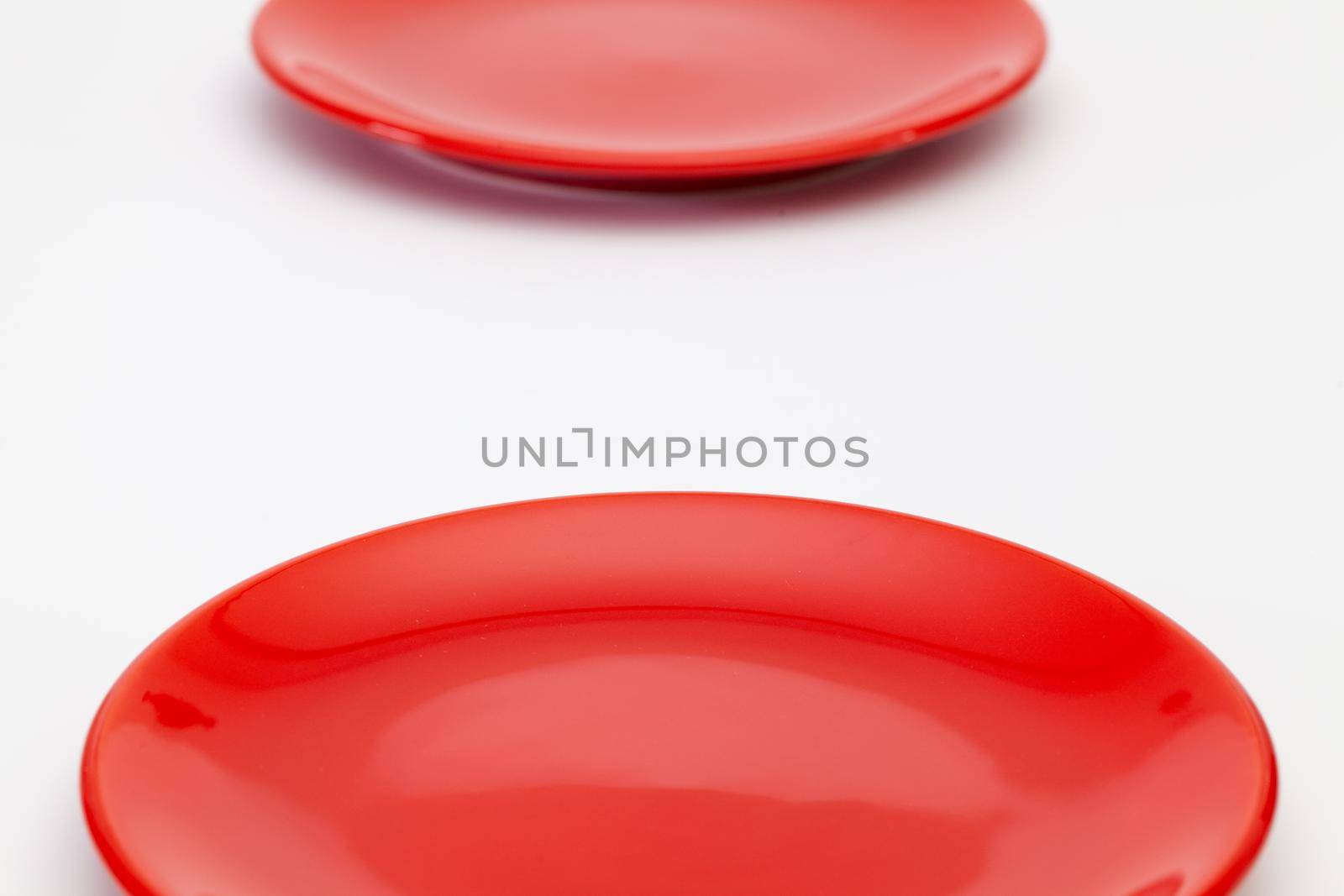Red plates on the white wooden table.Top view.  by CaptureLight