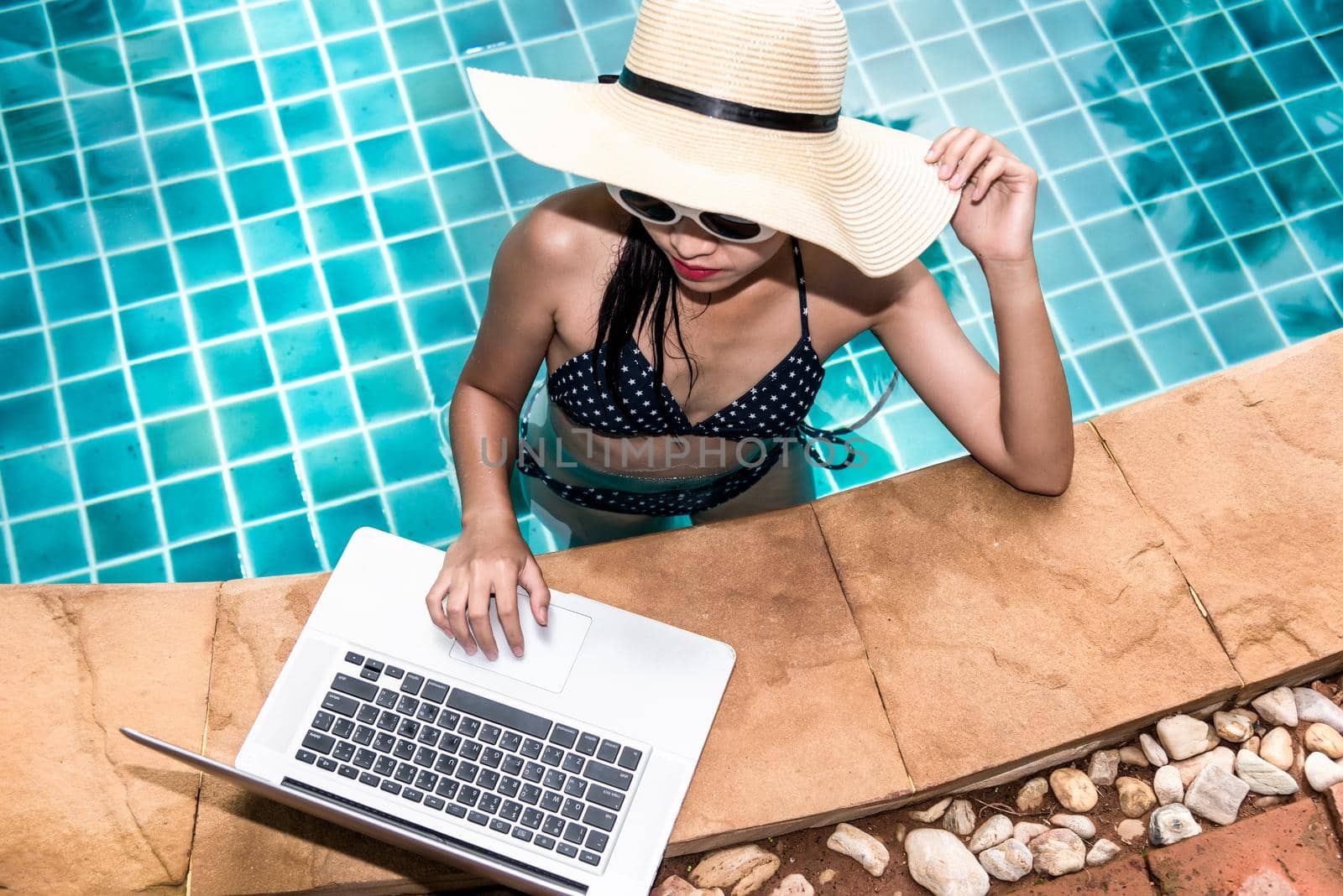 Portrait Beautiful woman using laptop from swimming pool in hotel by Sorapop