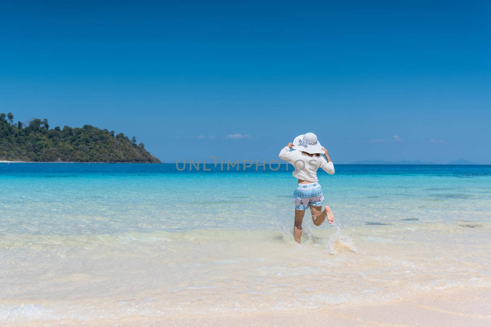 Happy young girl running to the beach by Sorapop