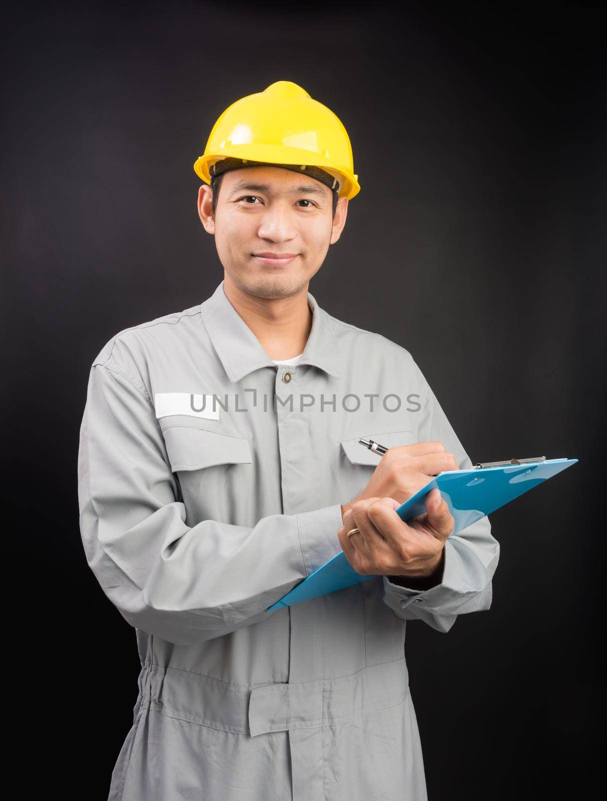 Handsome happy supervisor or technician writing notes clip board on black background