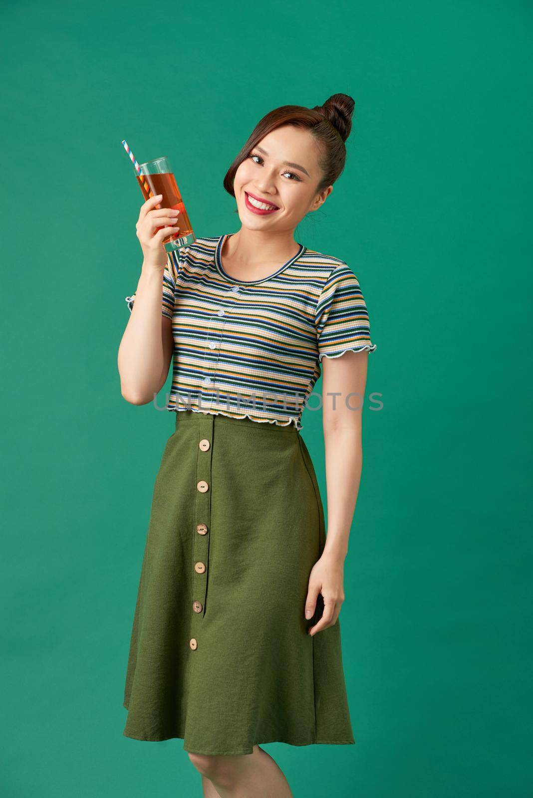 Laughing asian young woman holding soft drink and looking away.