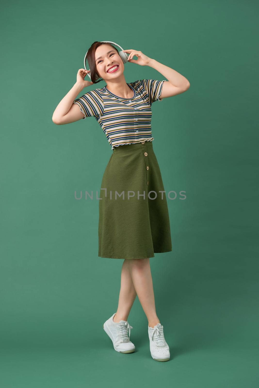 Music young girl dancing against isolated green background
