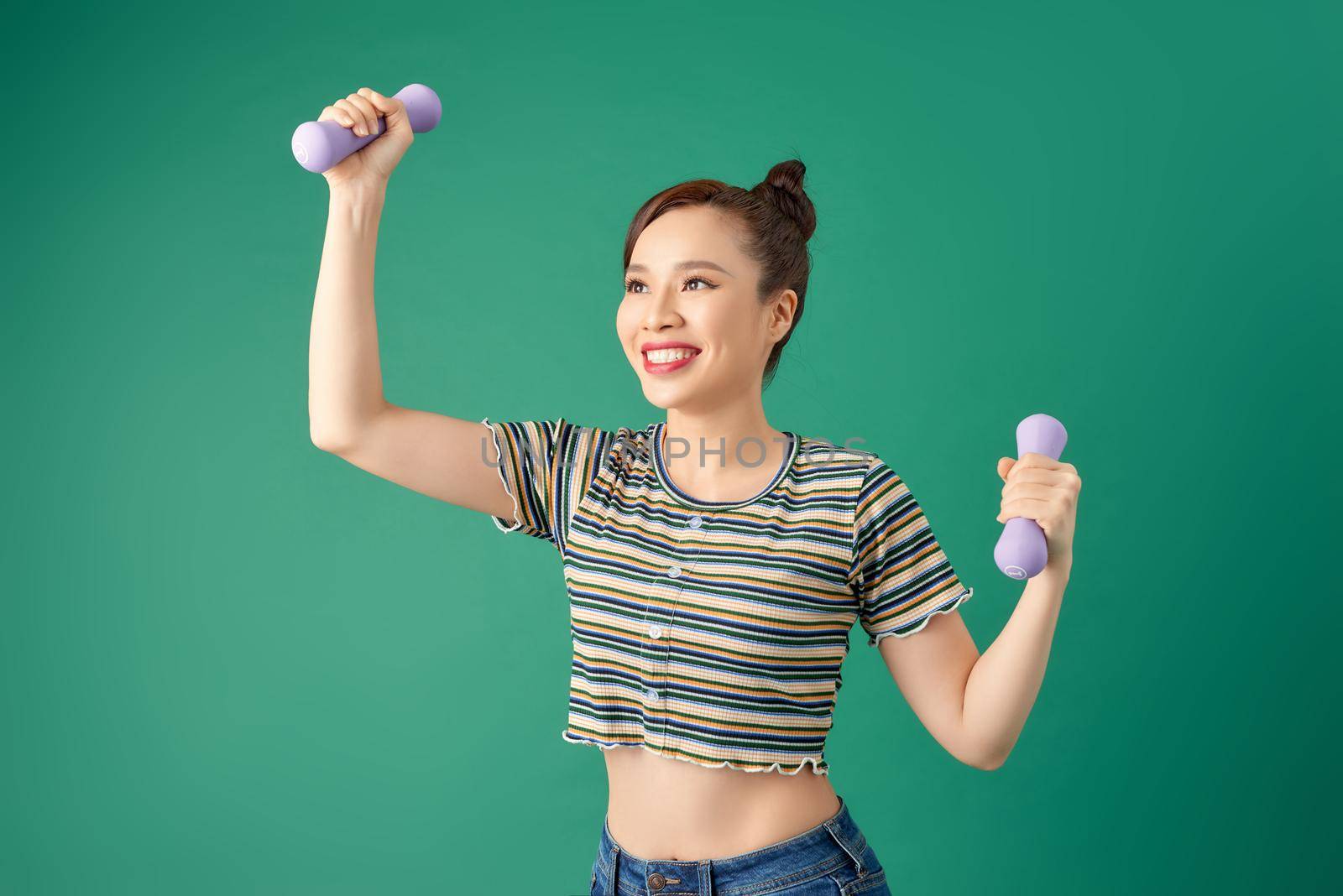 Young Asian woman in casual clothing with dumbell on green background. by makidotvn