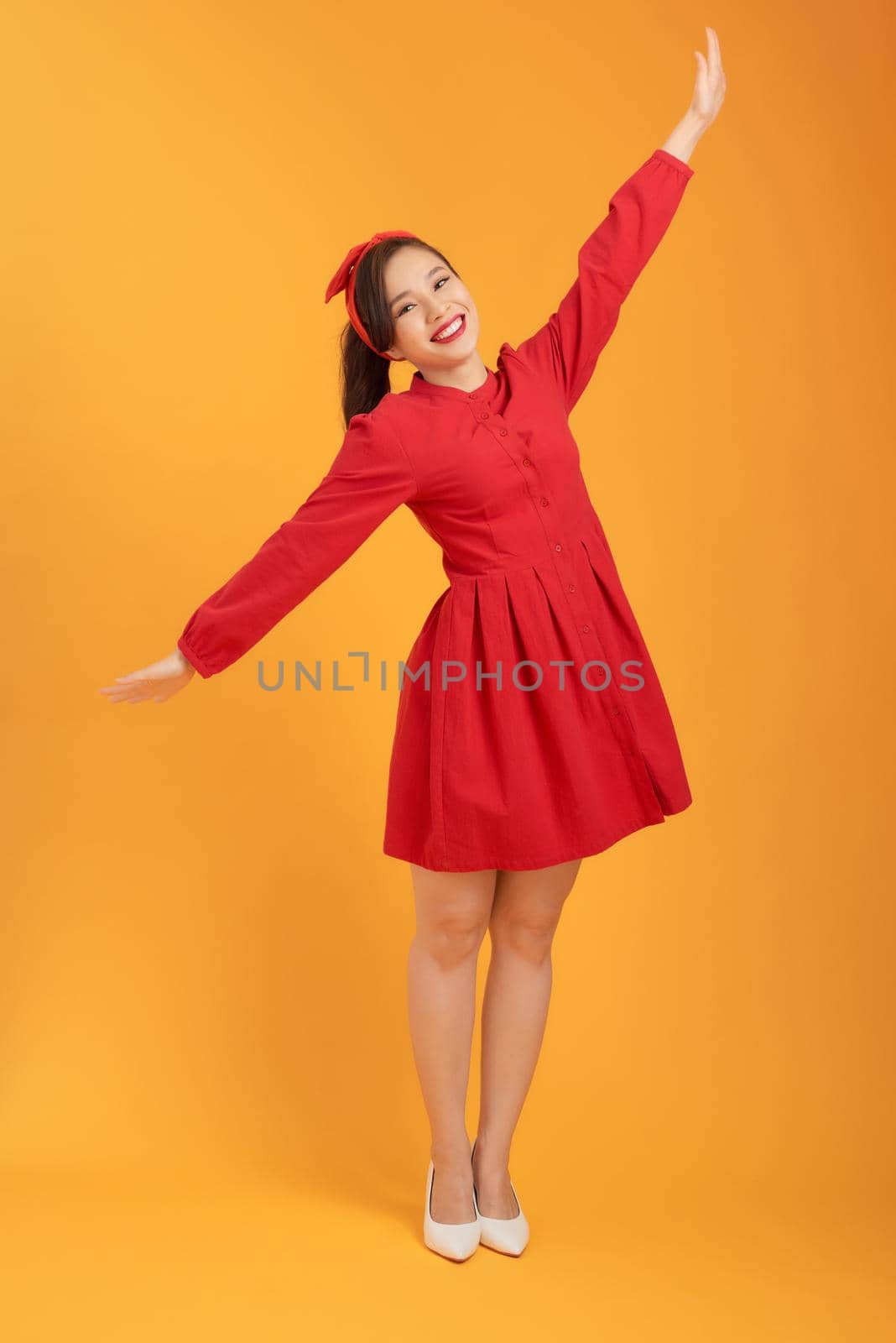 Beautiful lovely girl in red dress isolated on orange background in full body. by makidotvn