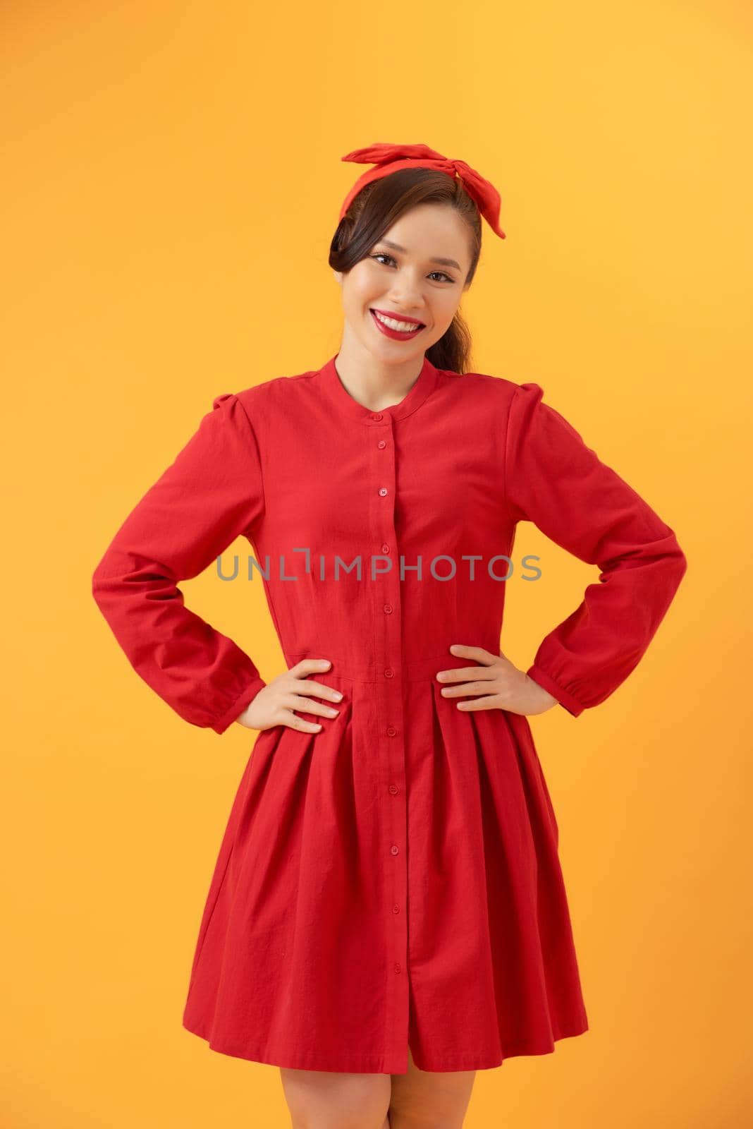 Portrait of cheerful young Asian woman standing over orange background.