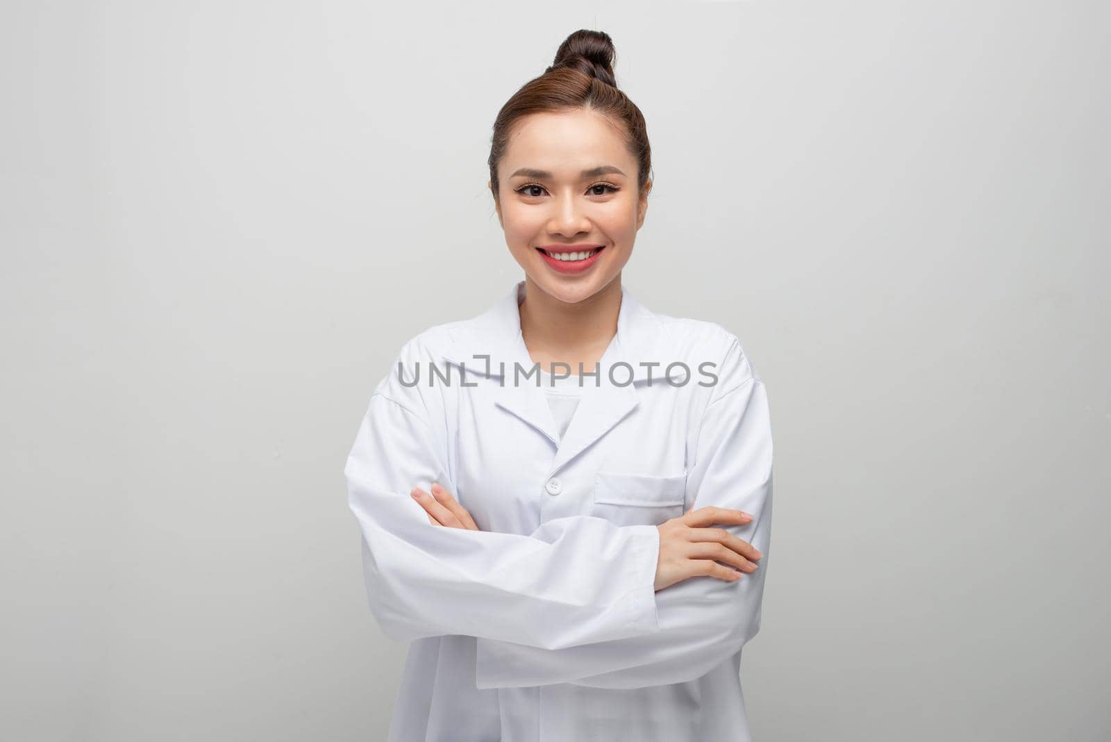Young doctor woman wearing coat standing over isolated white background with a happy and cool smile on face.