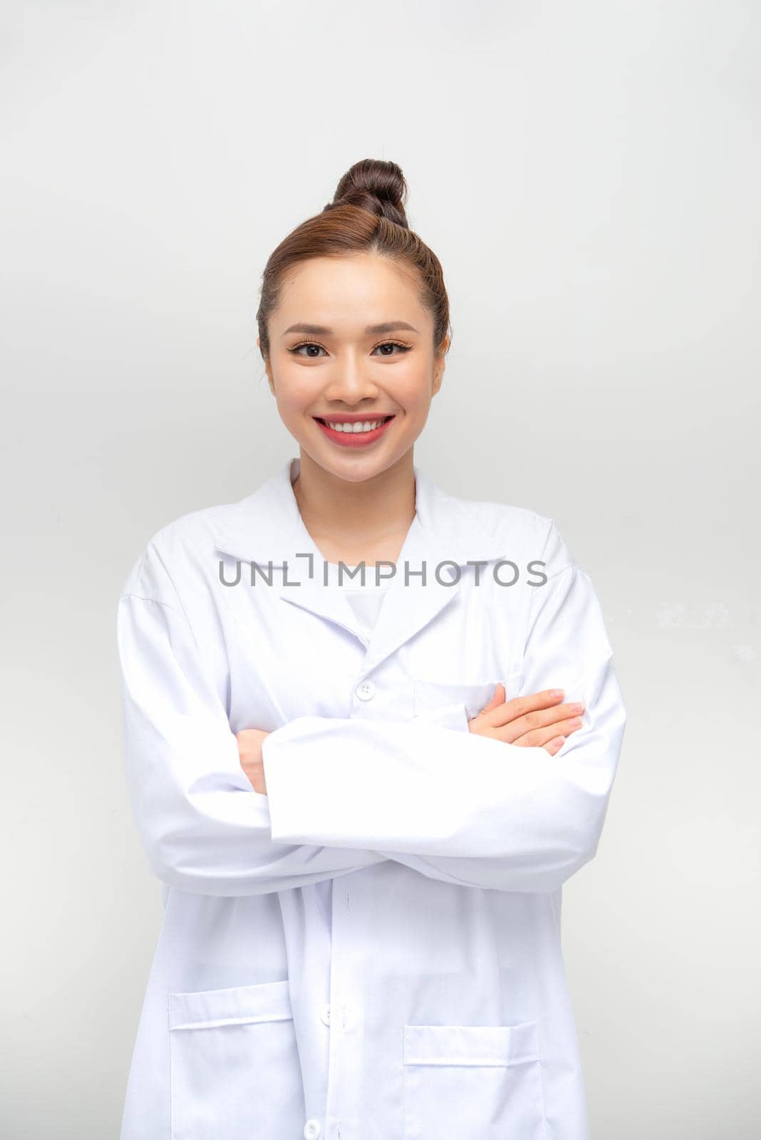 Young attractive female doctor with arms folded isolated on white