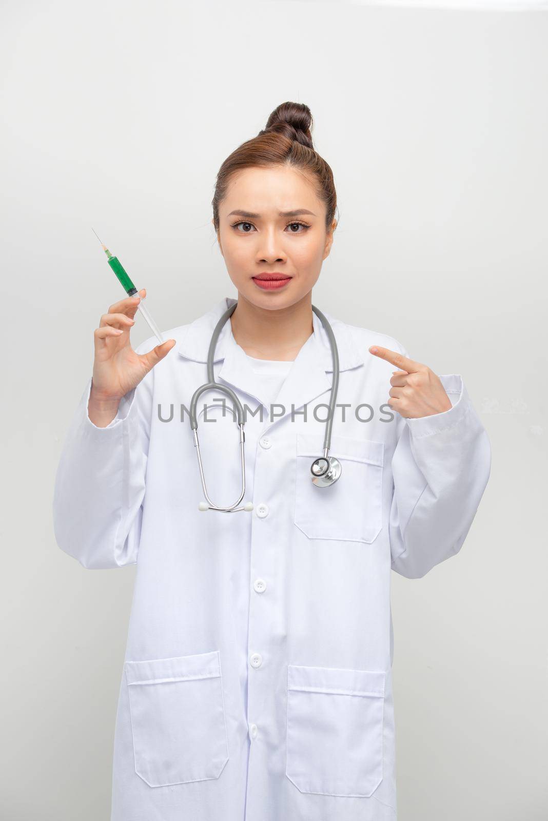 Doctor woman holding syringe with hand pointing, shocked with shame and surprise face, angry and frustrated. Fear and upset for mistake.