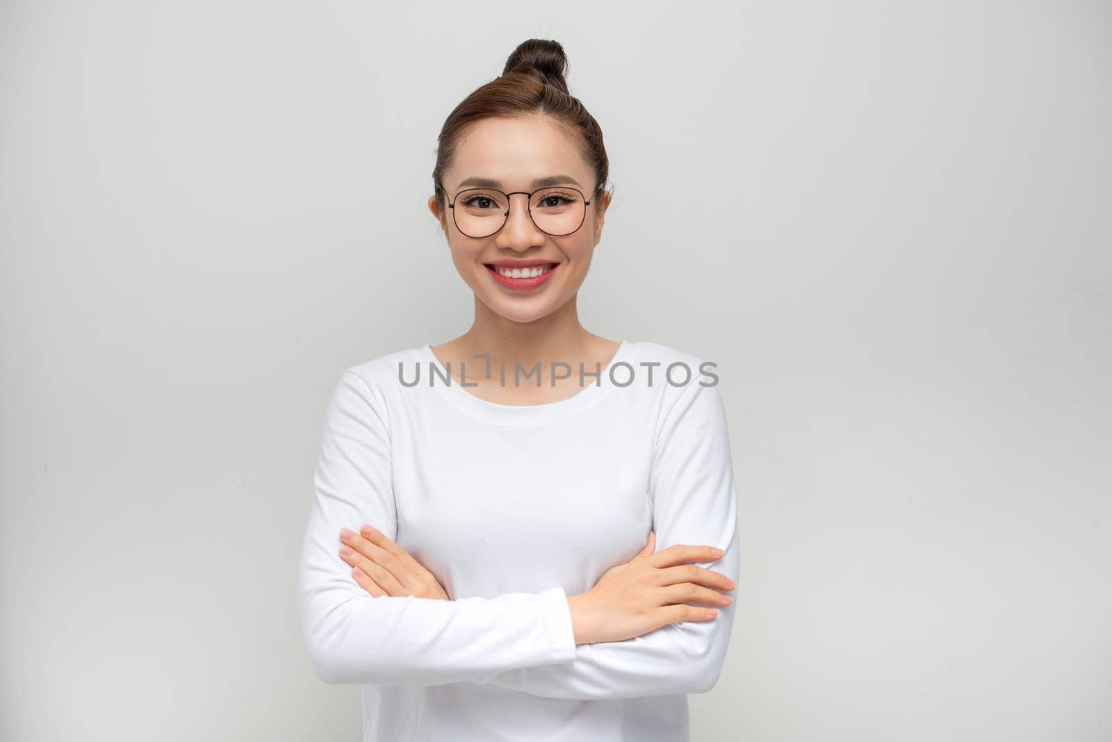 Young woman standing over isolated white background happy face smiling with crossed arms looking at the camera.