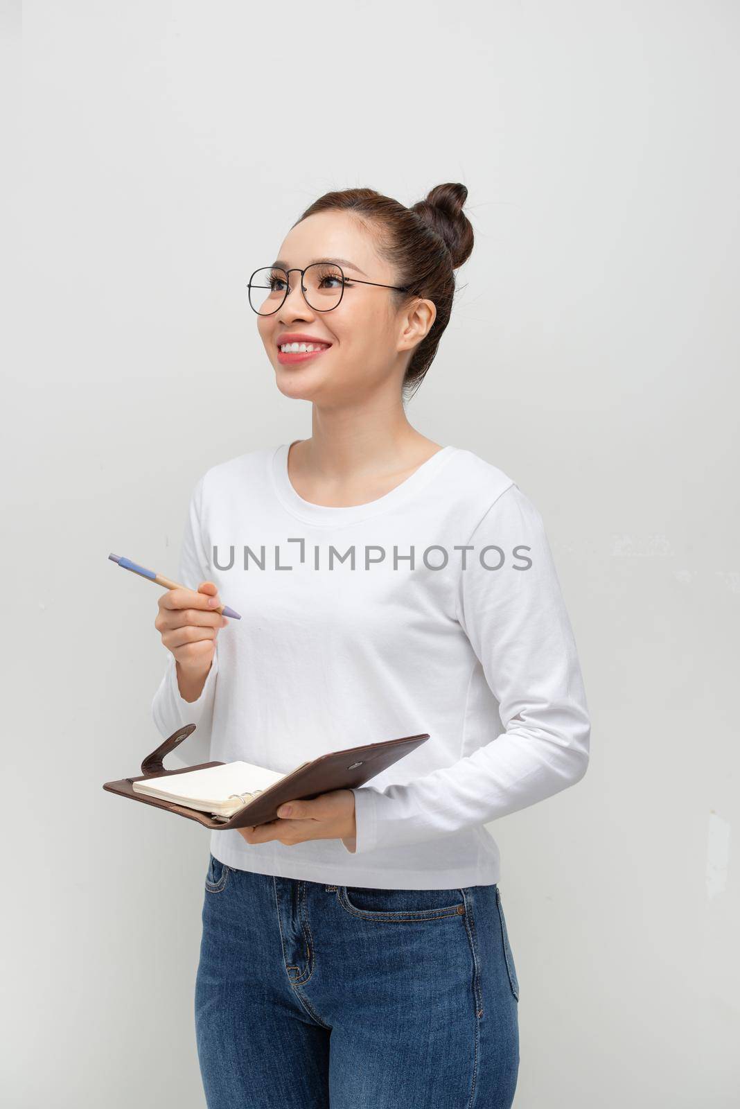 Serious pensive student girl reading her notes, holding pen and open notebook
