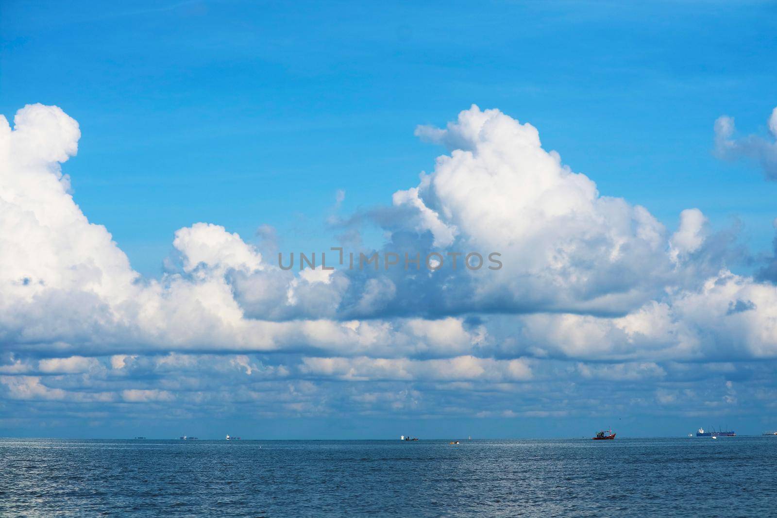 pure clear blue sky huge white gray cloud and sunlight shiny on tropical on the sea and fishing boat and cargo ship