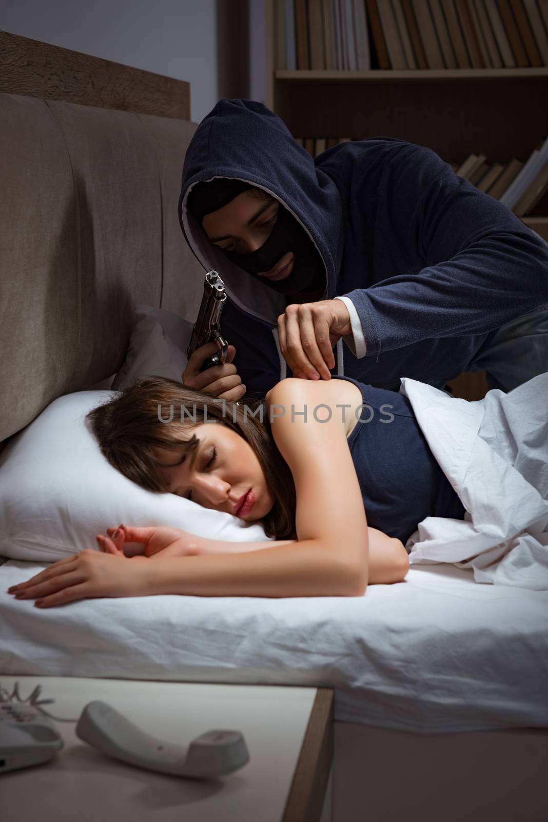 Burglar breaking into house at night to bedroom with sleeping woman