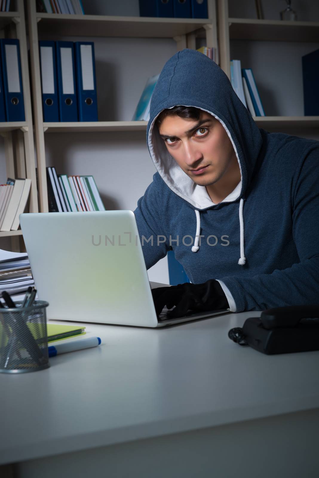 Young hacker hacking into computer at night