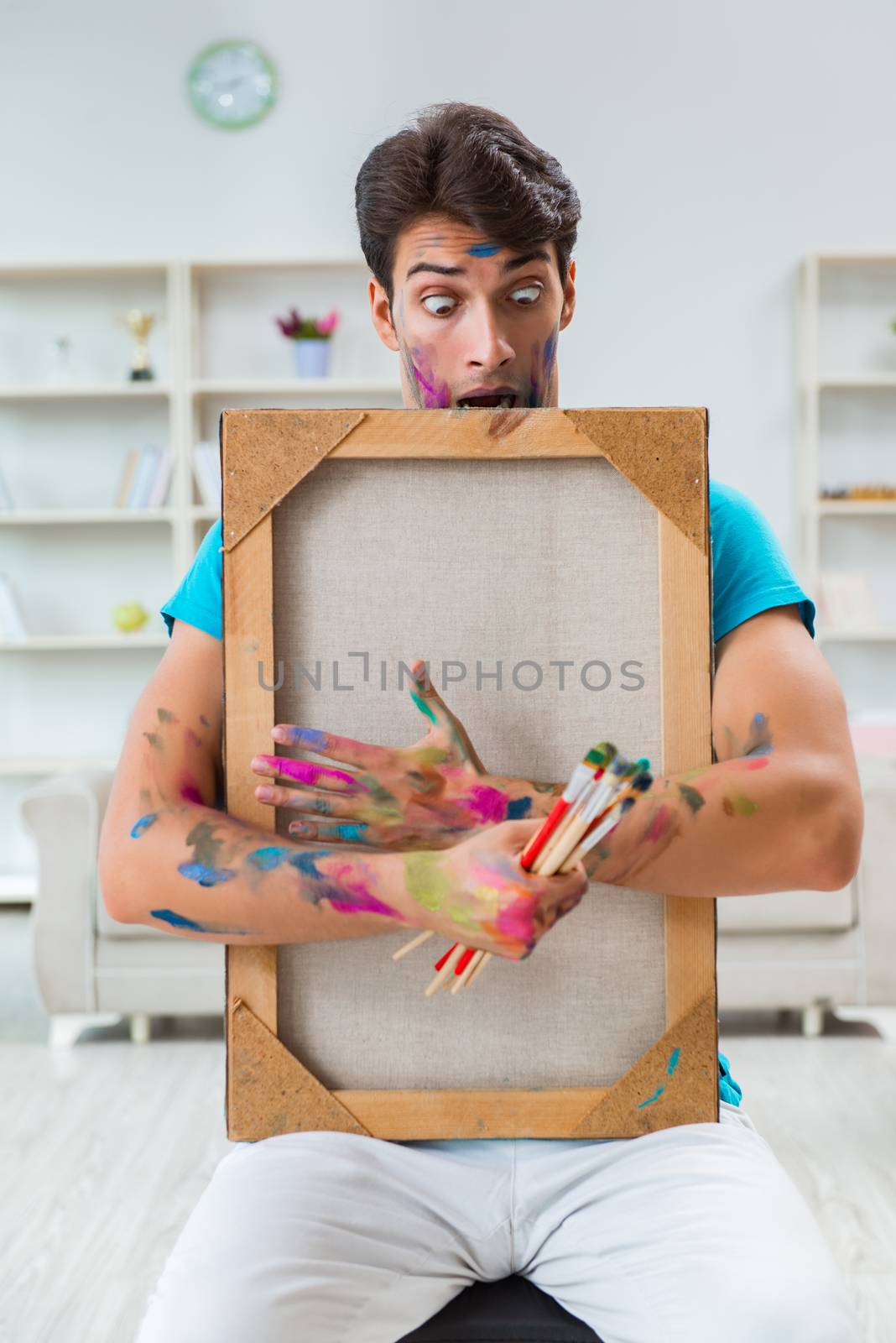 Young funny artist working on new painting in his studio