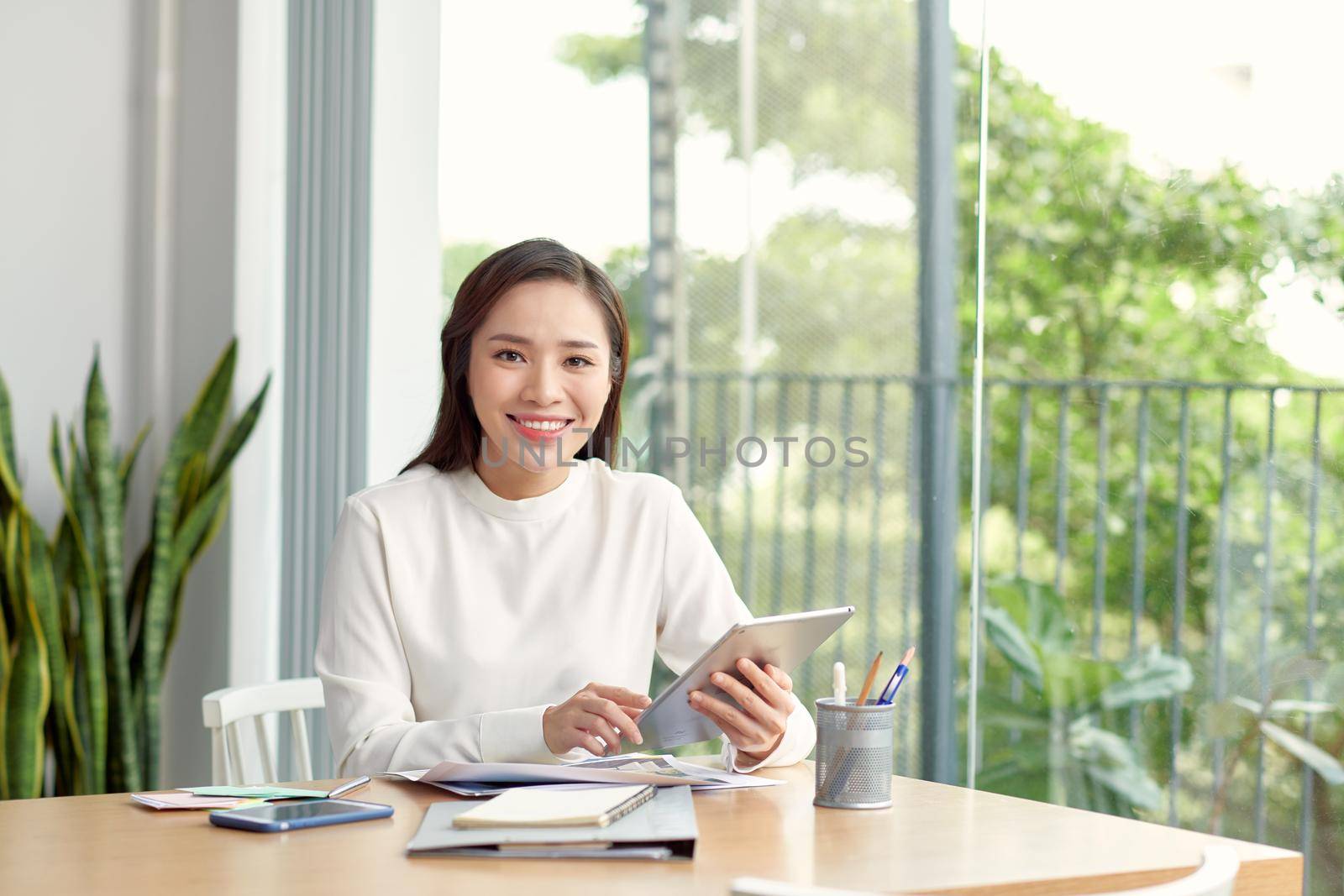 businesswoman smiling and working on tablet computer by makidotvn