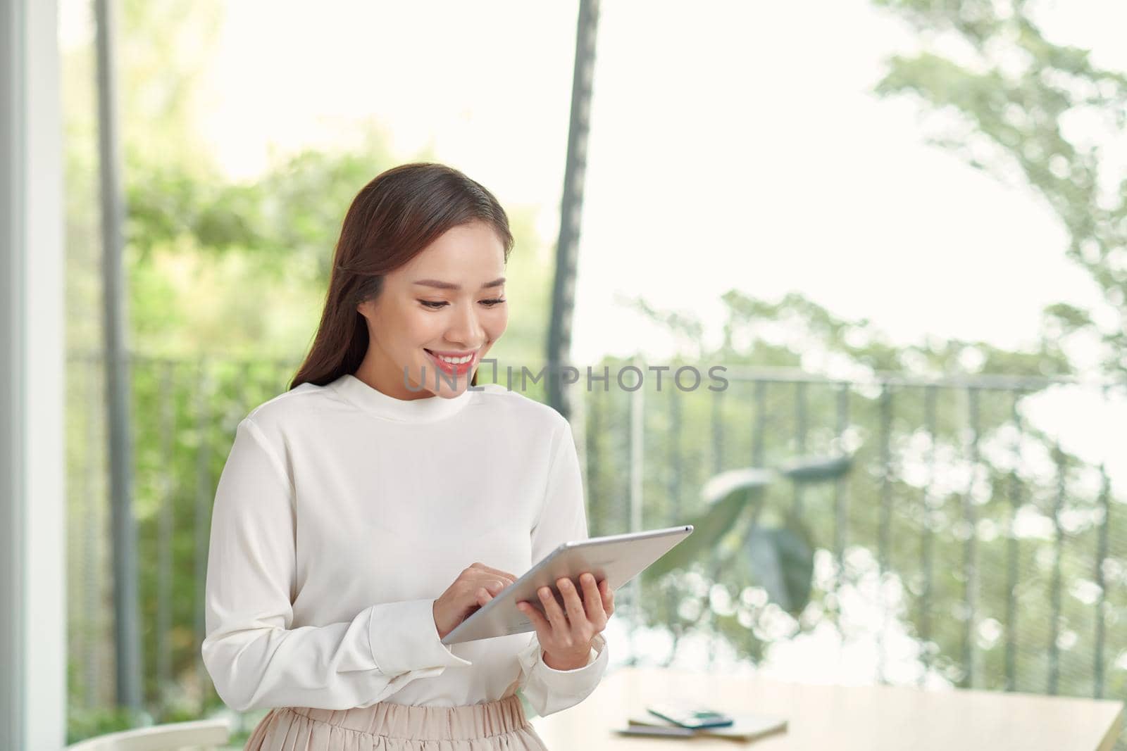 Beautiful asian woman using tablet in bright room by makidotvn