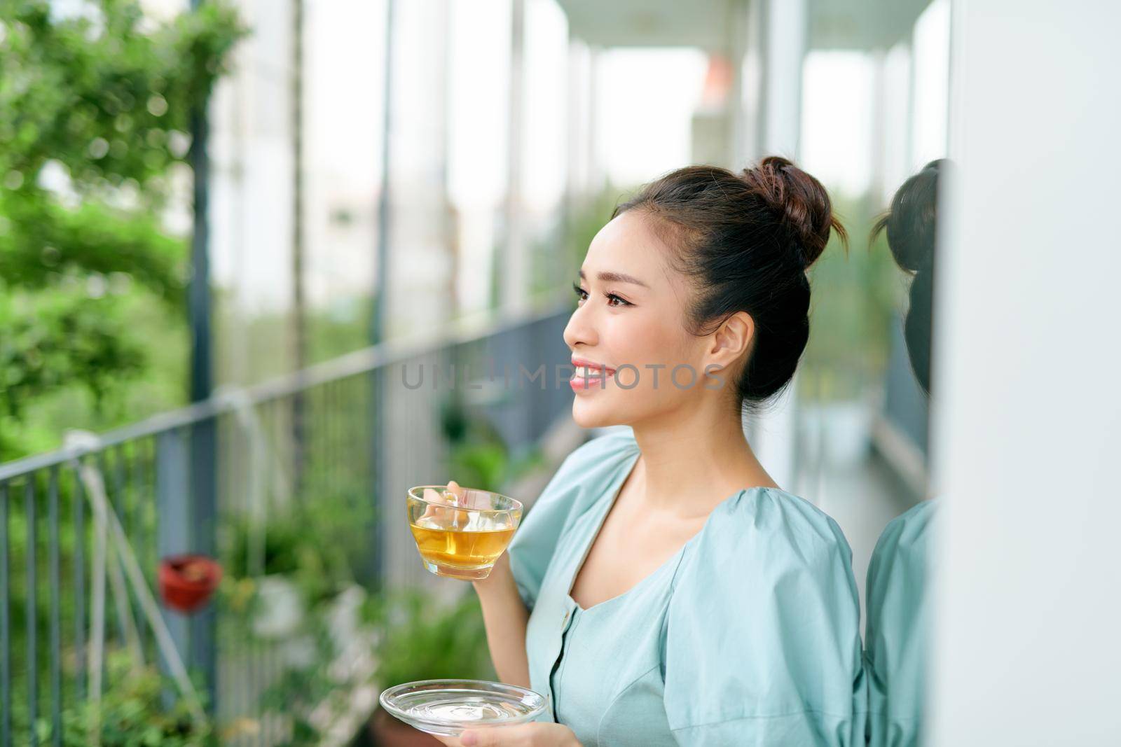 Beautiful girl on the balcony drinking tea