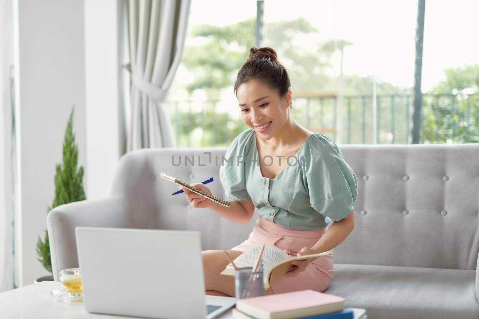 young woman browse internet noting something relaxing on sofa