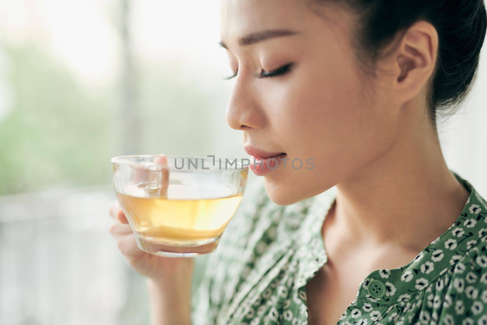 Beautiful young woman is looking out the window and holding a cup of tea