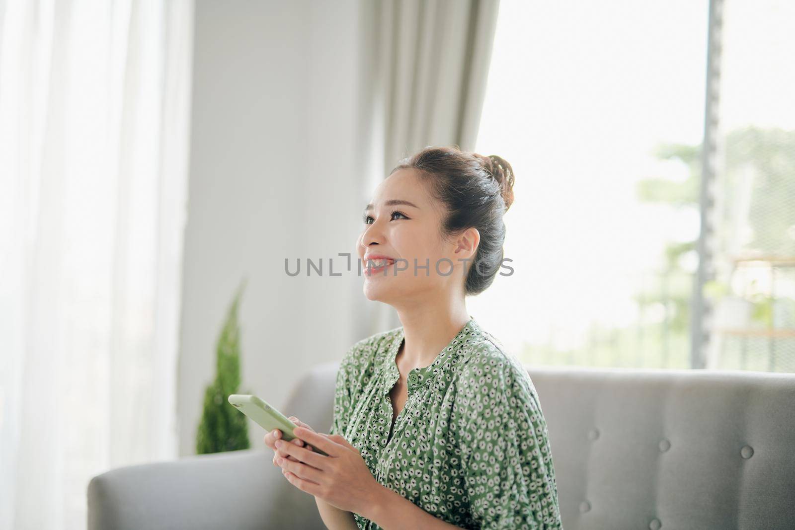 Smiling young  girl using funny mobile app laughing, playing game, chatting on cell at home.