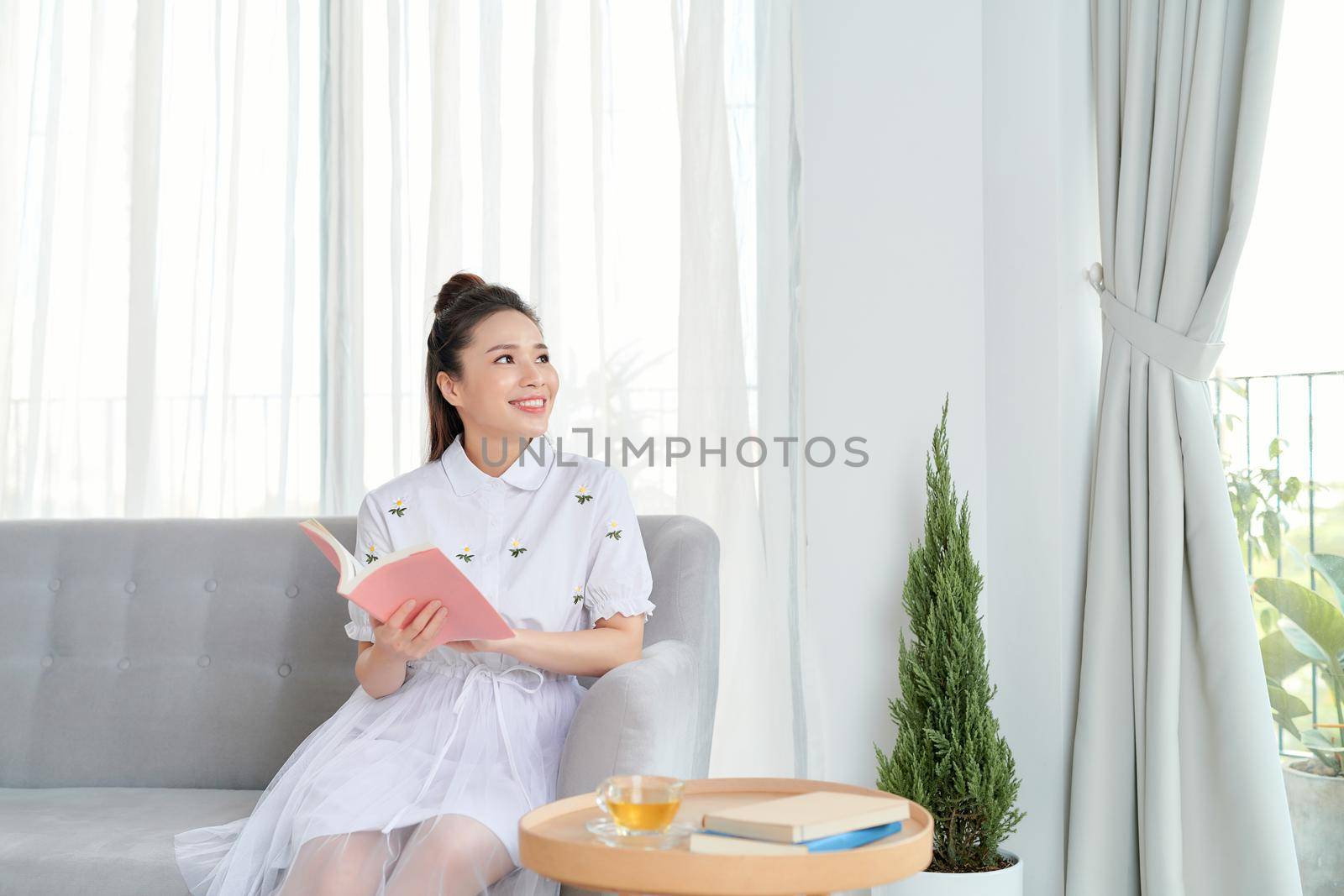 Portrait of a woman reading a book while relaxing on the couch