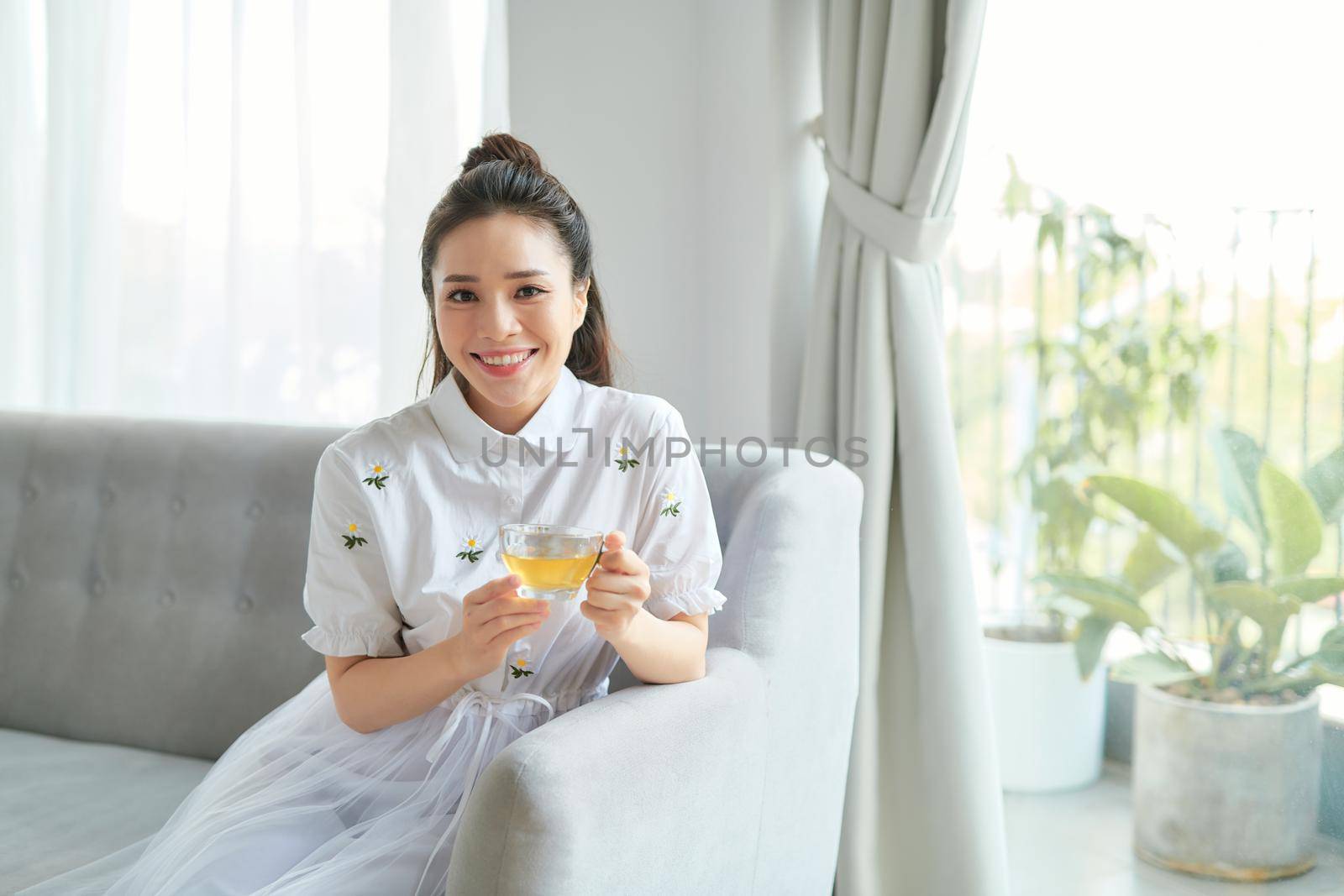 Young woman sitting in sofa and drinking tea.