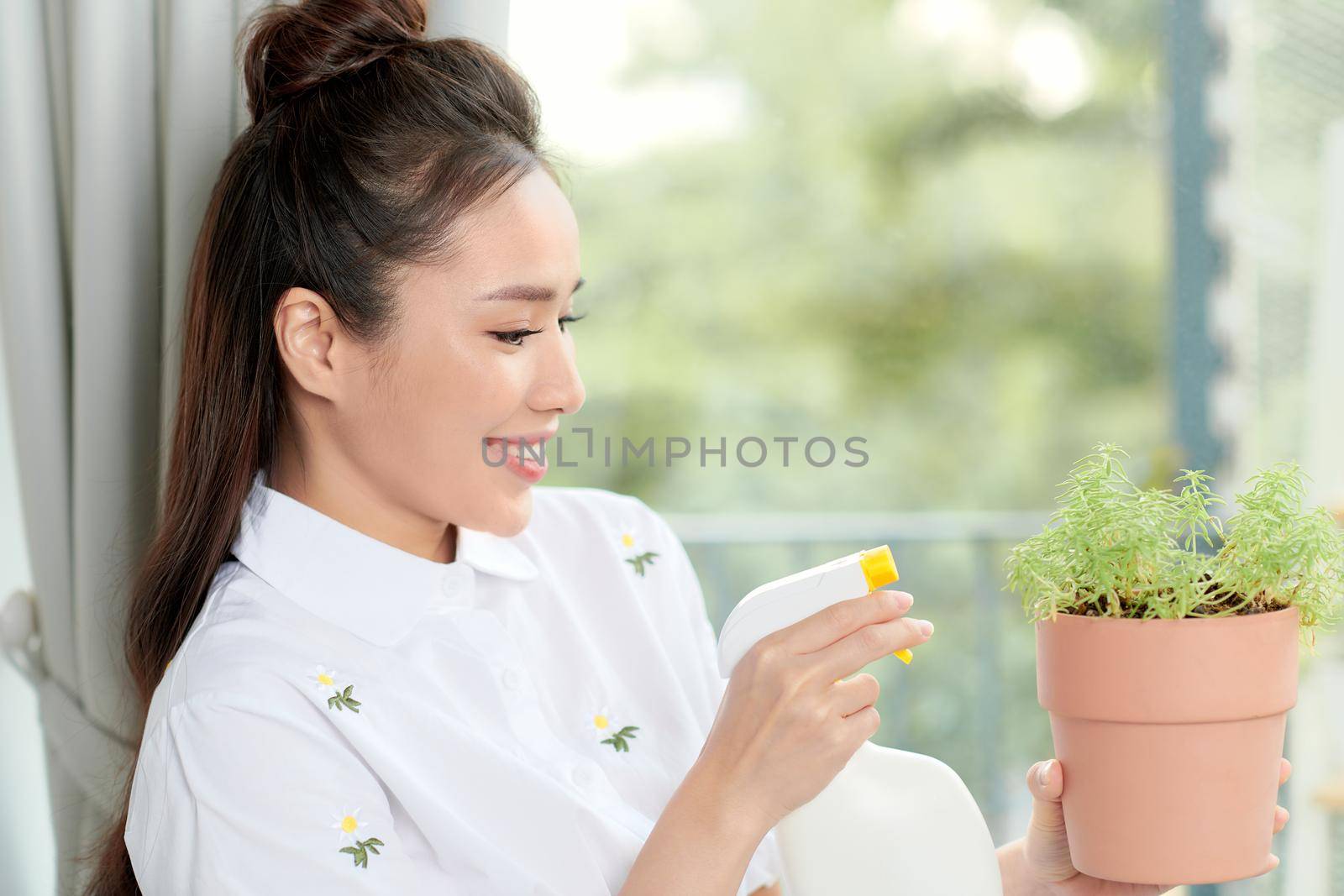 Young woman with potted plants on a garden balcony. Floriculture is a hobby. 