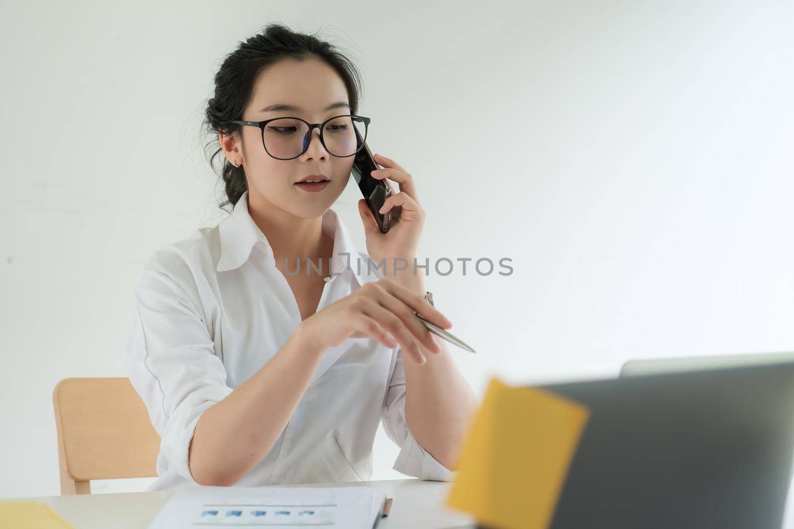 Busy Business woman discuss with cilent by video call and talking with cell phone. female technical support agent trying to explain something to a client while working on laptop at call center. by itchaznong