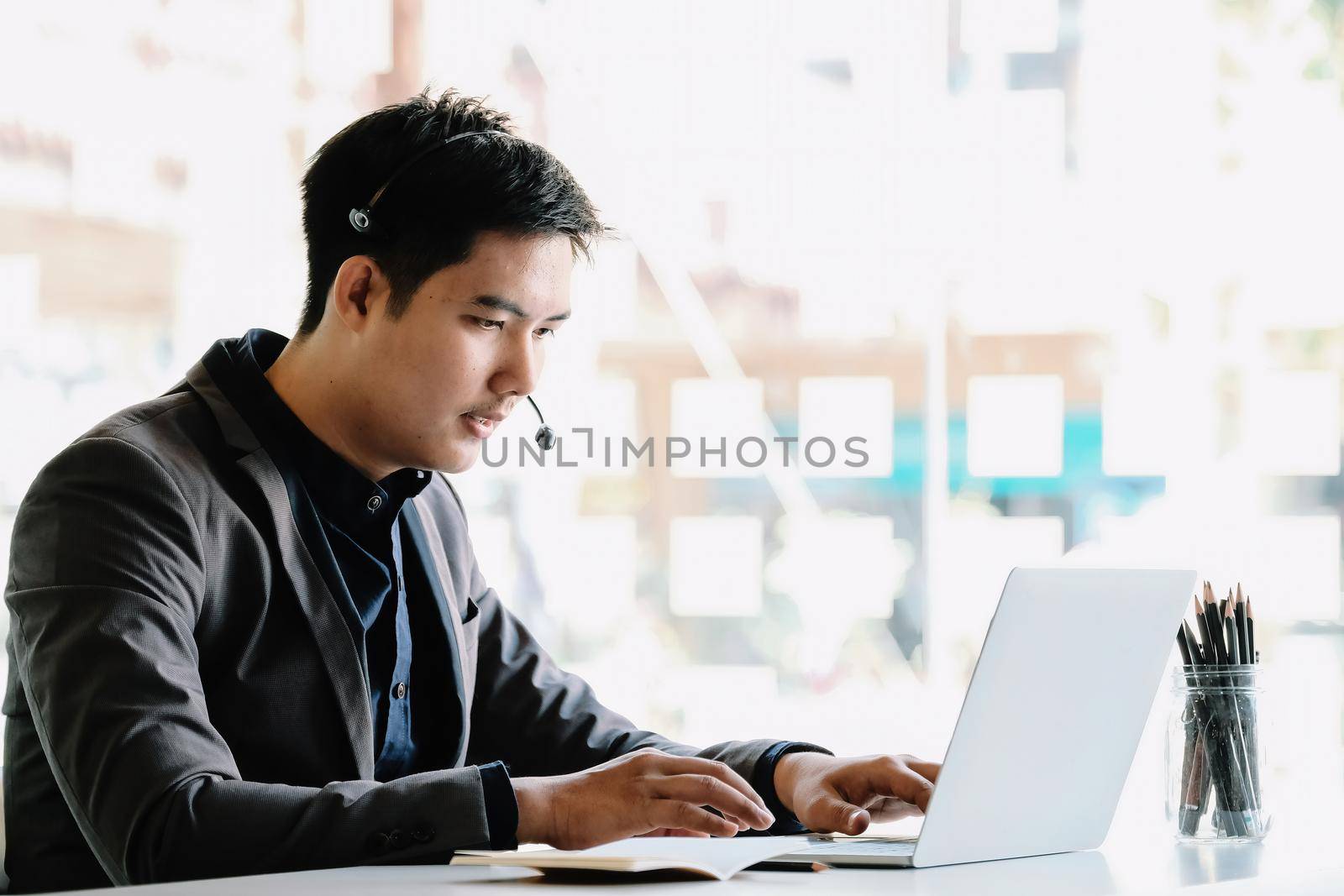 young businessman wearing wireless headset with microphone, involved in online video call negotiations meeting with partners colleagues or studying distantly at home.