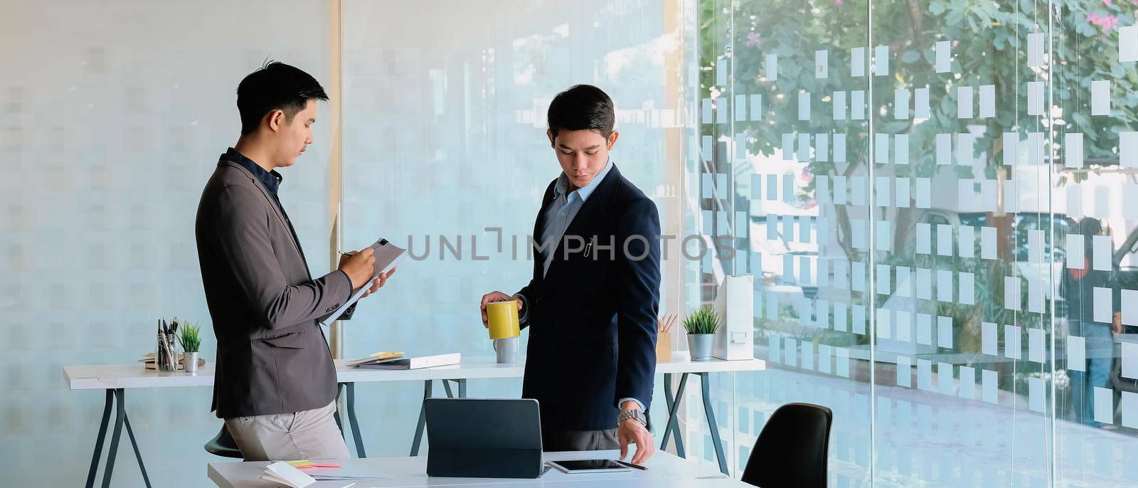 Two asian businessman discussing and marketing plan in moderm office by nateemee