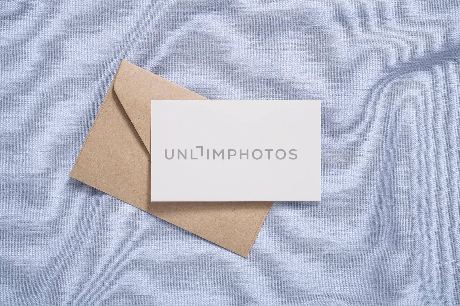 White blank paper card and envelope mockup on blue neutral colored textile