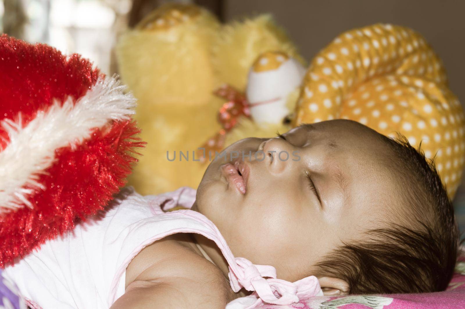 Close up face of cute sleeping newborn baby boy in drowsy eyes sleepy mood lying on bed. Portrait One Sweet little infant toddler. Indian ethnicity. Front view. Child care peace tranquil background.