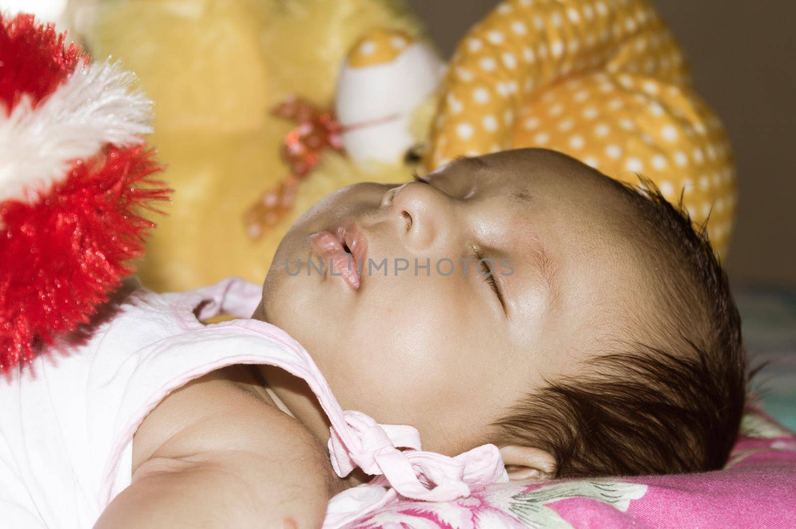 Close up face of cute sleeping newborn baby boy in drowsy eyes sleepy mood lying on bed. Portrait One Sweet little infant toddler. Indian ethnicity. Front view. Child care peace tranquil background.