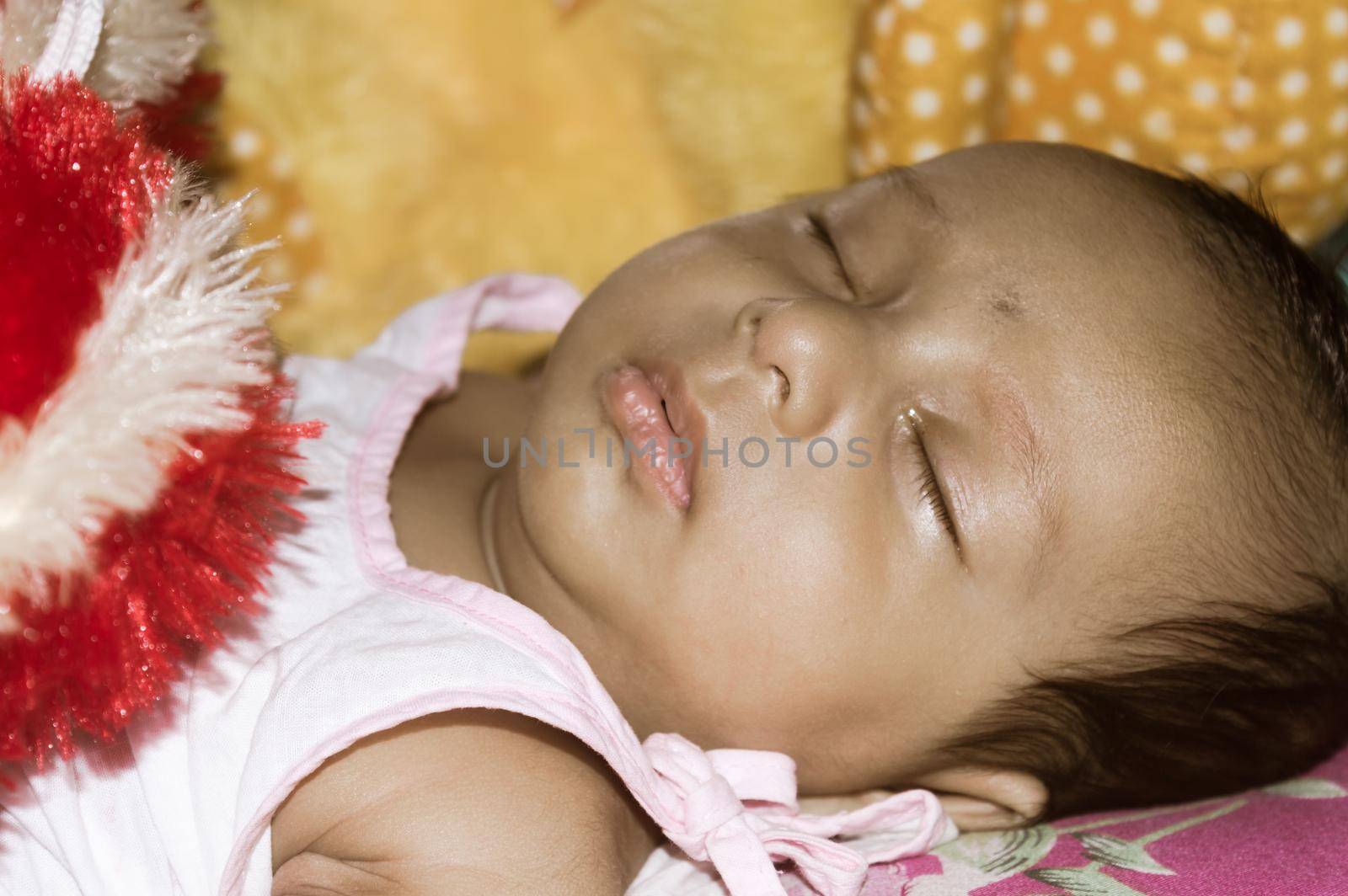 Close up face of cute sleeping newborn baby boy in drowsy eyes sleepy mood lying on bed. Portrait One Sweet little infant toddler. Indian ethnicity. Front view. Child care peace tranquil background.
