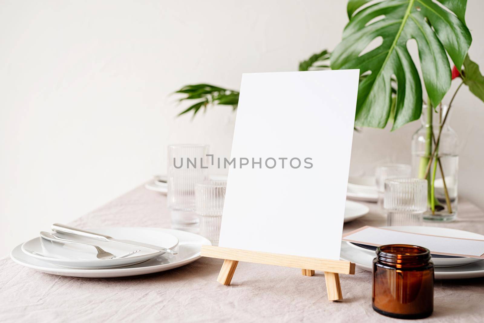 Mock up label the blank menu frame in bar restaurant, Stand for booklets with white paper, wooden tent card on restaurant table with tropical bouquet