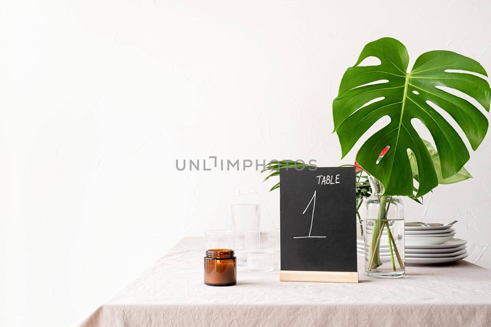 Mock up table tent with words table 1 on restaurant table with tropical bouquet. Black chalk table tent