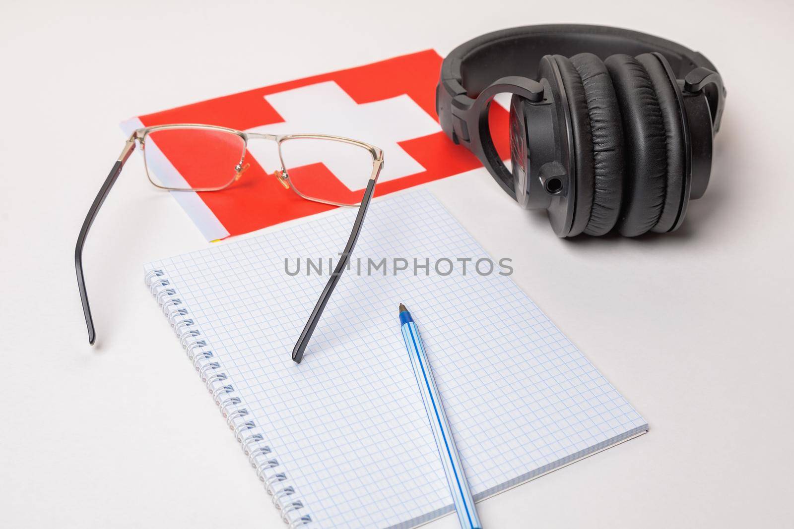Learning foreign languages in Switzerland with audio recordings and headphones. Notepad, glasses, pen.