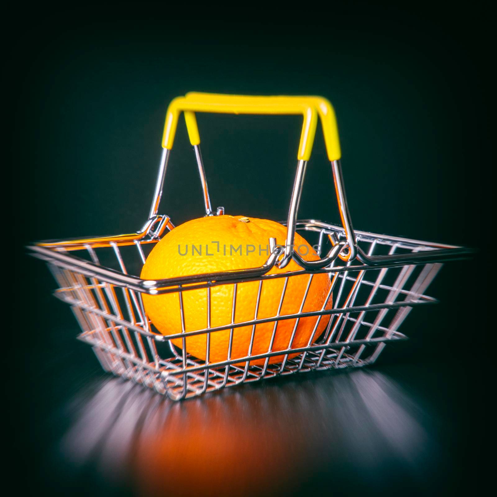 steel supermarket basket with orange on black background close-up by roman112007