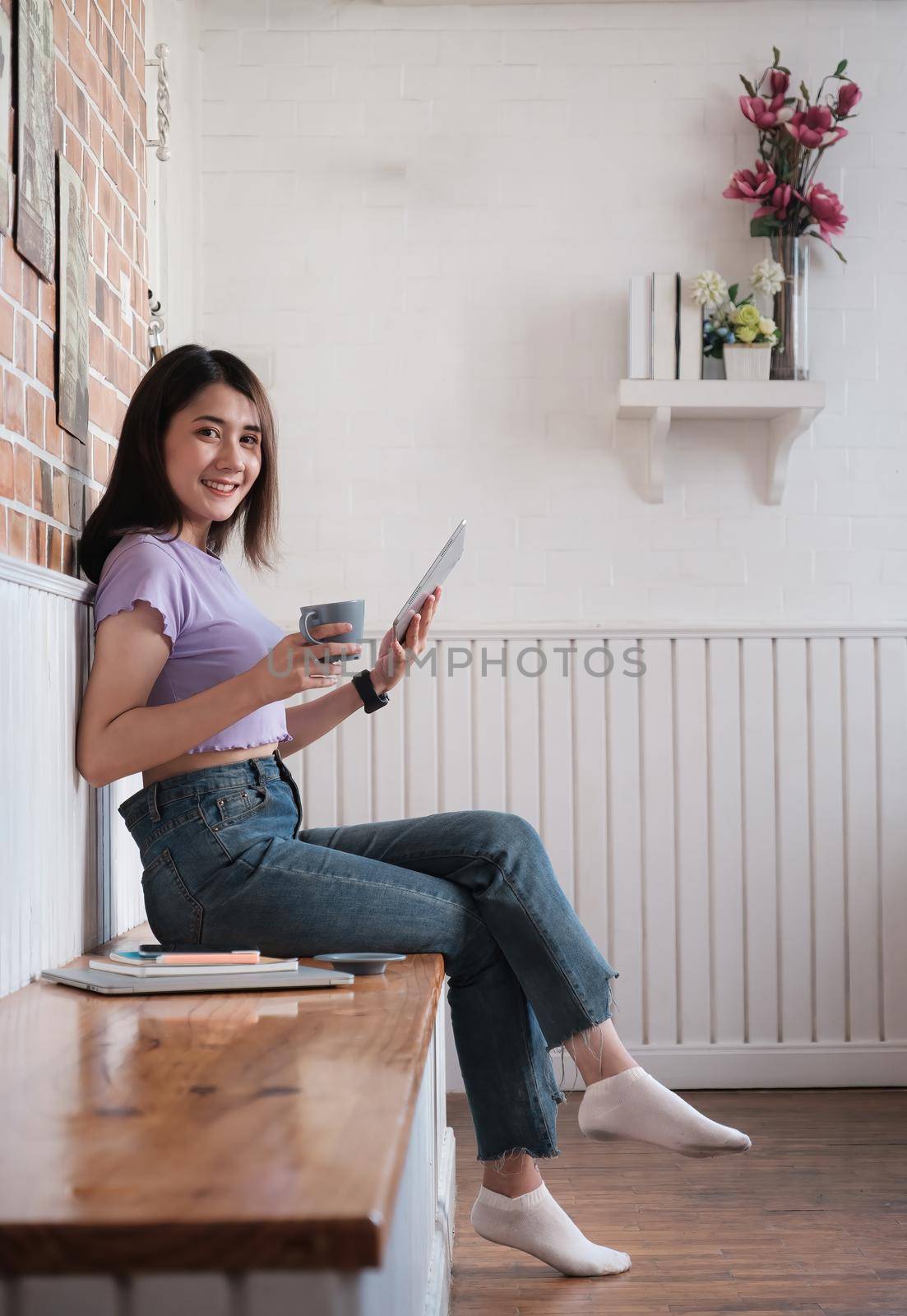 Smiling young asian woman entrepreneur checking order by digital tablet while sitting at her home office. Work From Home concept