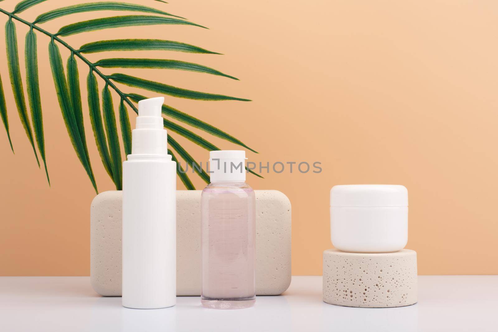 Set of natural organic beauty products for daily skin care with beige podiums against beige background with palm leaf by Senorina_Irina