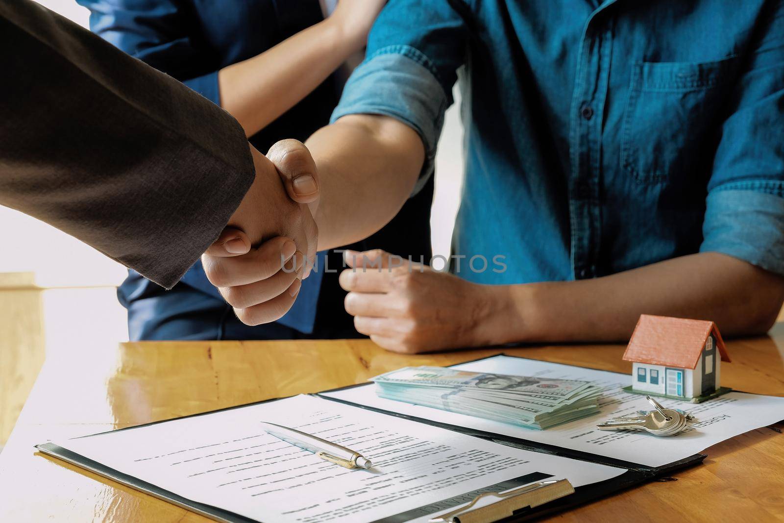 married couple and friendly realtor shaking hands after making real estate deal indoors, above view