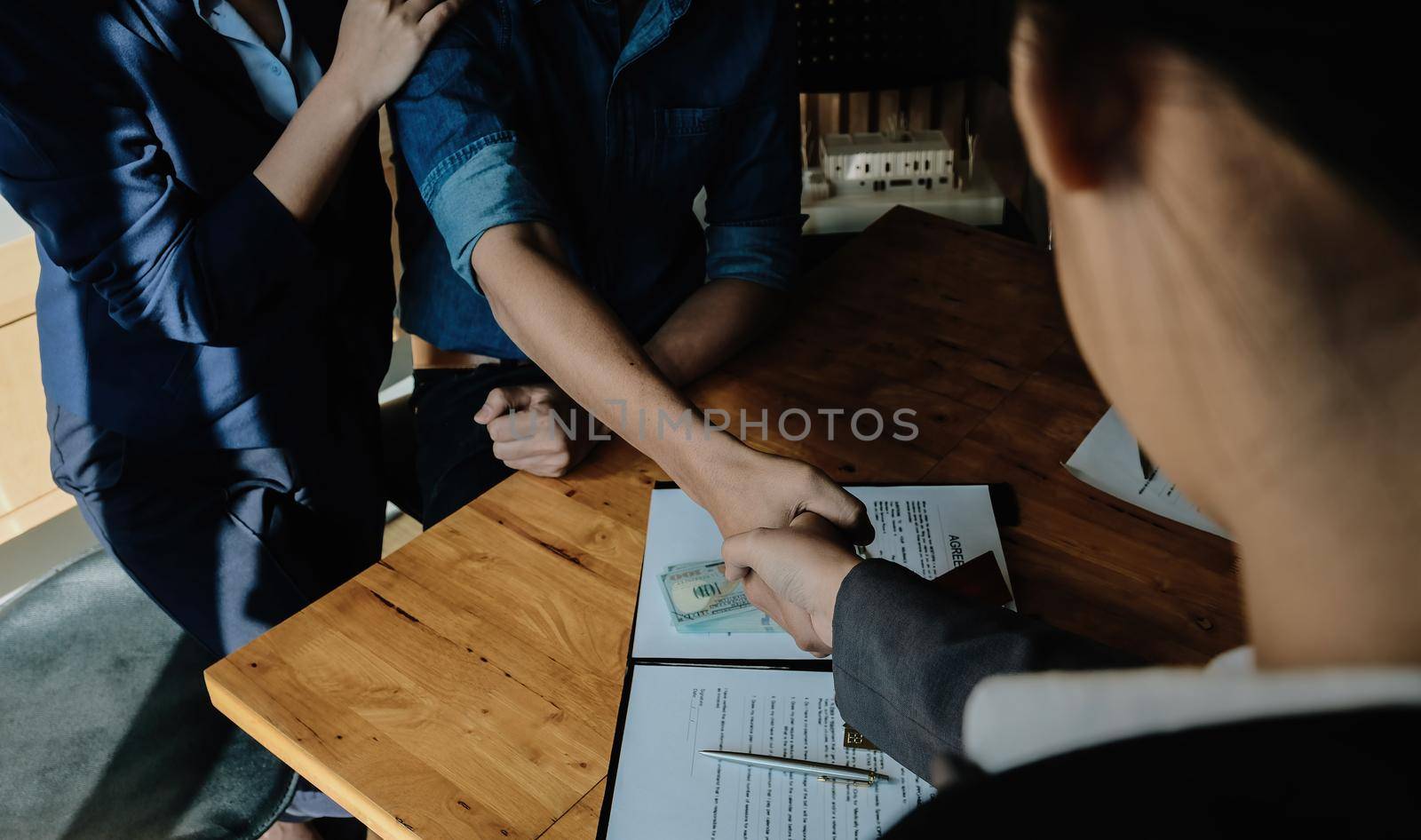 Above view of married couple and friendly realtor shaking hands after making real estate deal indoors, above view