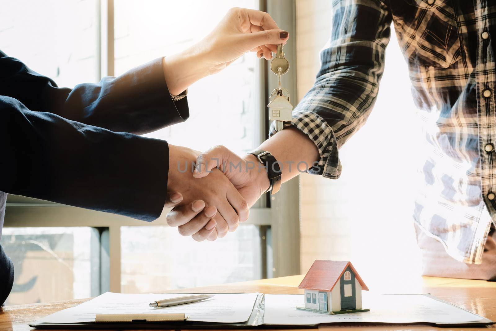 Real estate agent and customers shaking hands together celebrating finished contract after about home insurance and investment loan, handshake and successful deal.