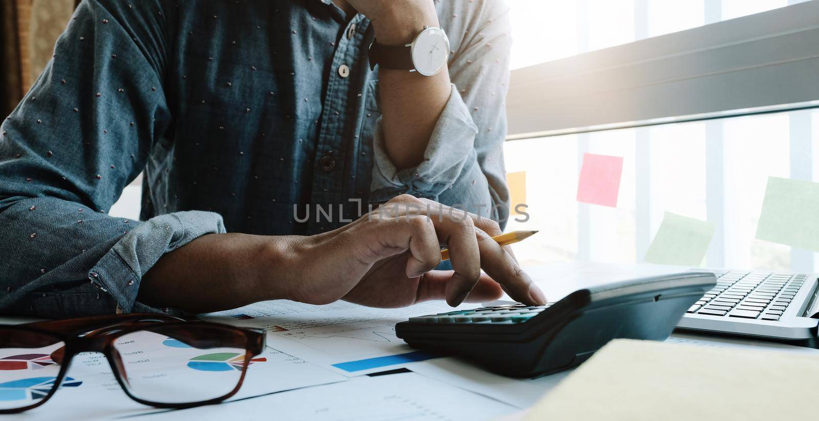 Business woman working in finance and accounting Analyze financial budget with calculator and laptop computer in the office.