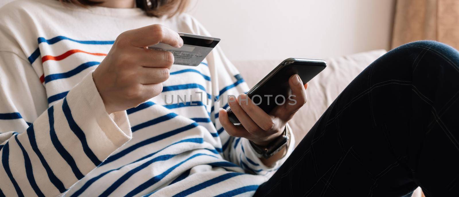 Online shopping payment,Woman's hands holding a smart phone and credit card and for online shopping at home.