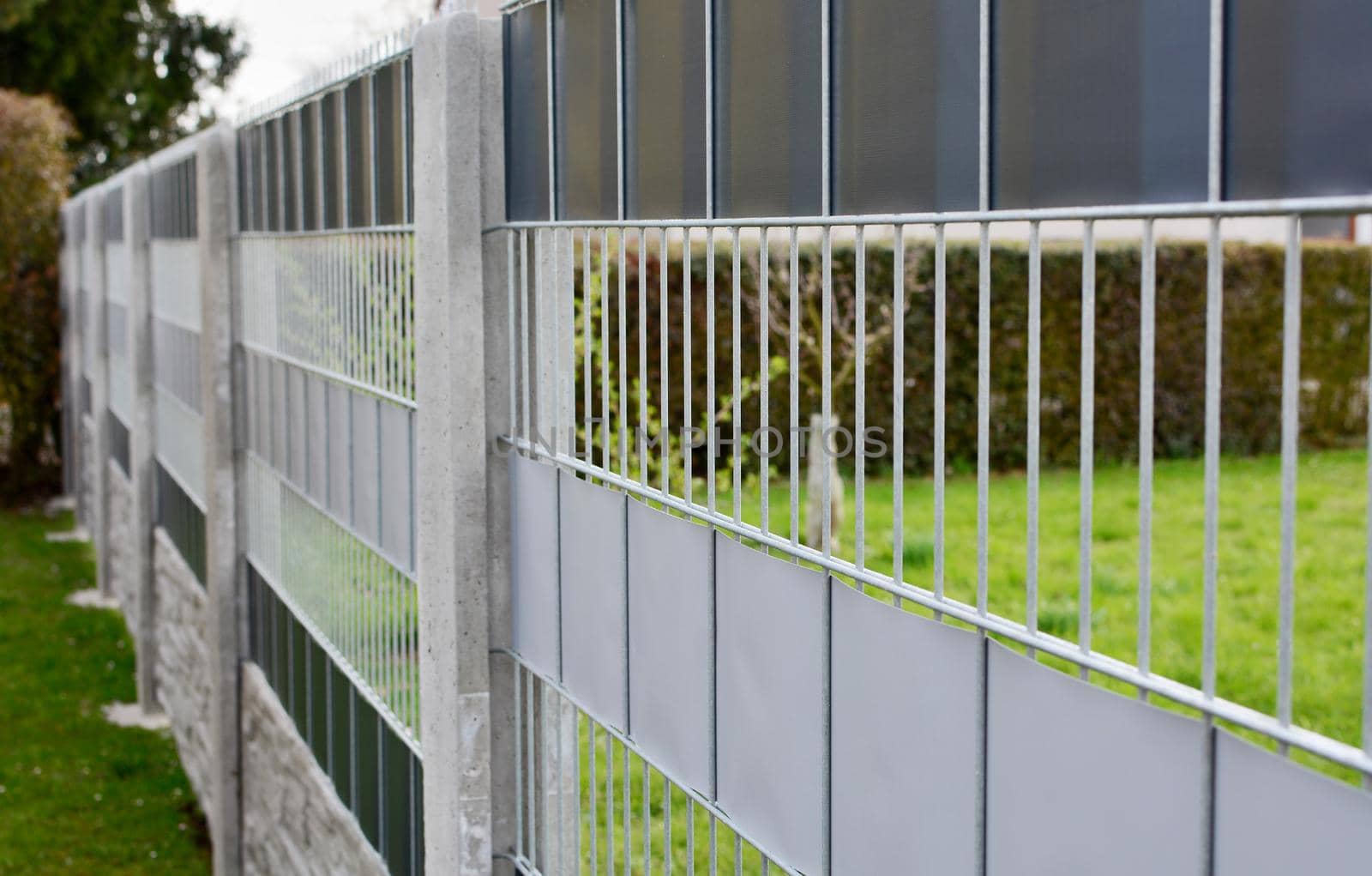 Garden fence made with decorative galvanized wire fence panels inserted in to the concrete columns.