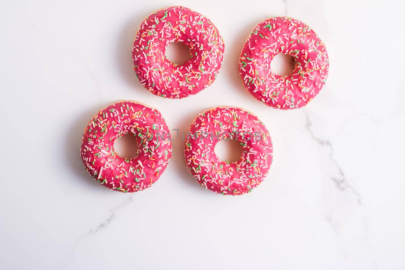 Bakery, branding and cafe concept - Frosted sprinkled donuts, sweet pastry dessert on marble table background, doughnuts as tasty snack, top view food brand flat lay for blog, menu or cookbook design